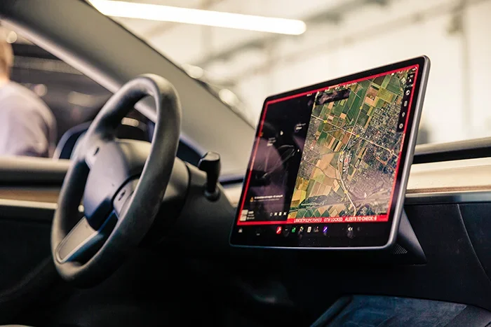 Das Bild zeigt das Cockpit eines Teslas. Zu sehen ist eine interaktive Karte auf dem Display des Teslas, die die Navigation erleichtert.