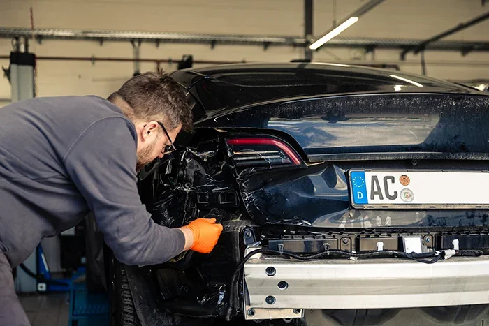Ein Kfz-Mechatroniker führt Karosseriereparaturen an einem Tesla im Tesla Approved Body Shop in der Werkstatt von Cremer und Sohn in Düren durch.